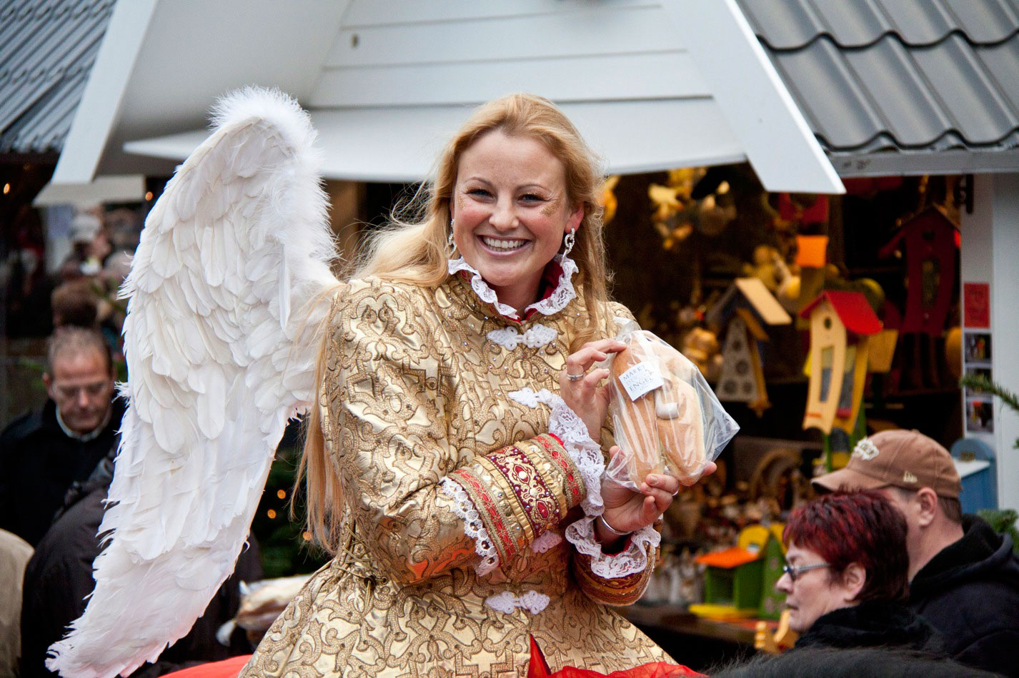 Eine Frau als Engel verkleidet lächelt auf dem Kölner Weihnachtsmarkt 'Markt der Engel'.