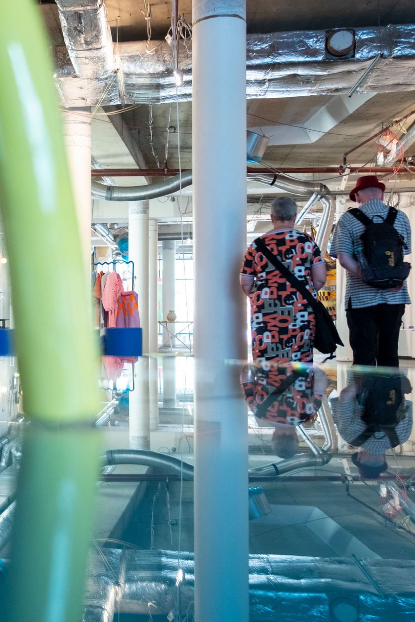 In einem hellen industriellen Raum sind bunte Kunstwerke und Gegenstände verteilt.