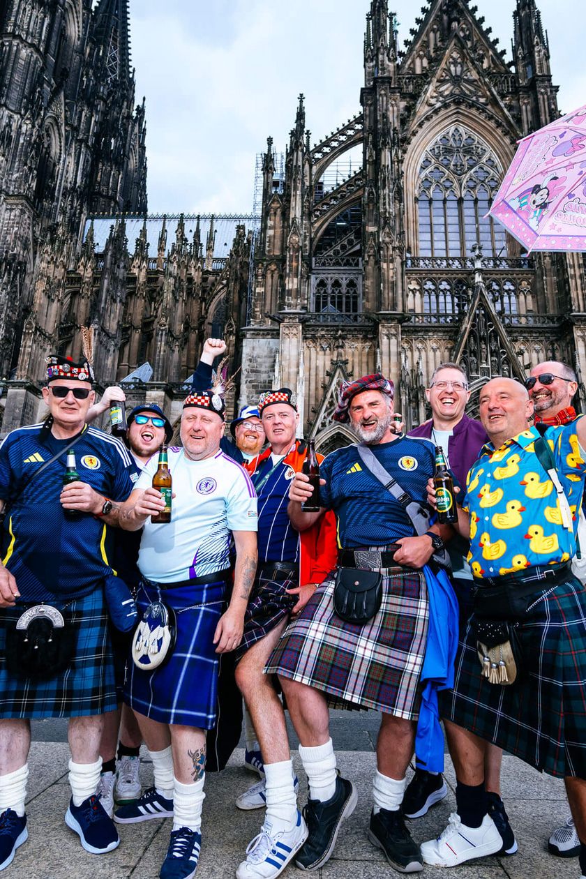 Dreizehn Männer stehen vor dem Kölner Dom. Einige von ihnen tragen einen Kilt.