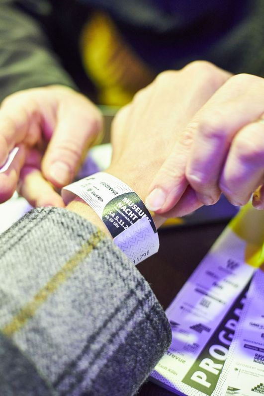 Ein Festivalbändchen wird einem Handgelenk umgebunden.