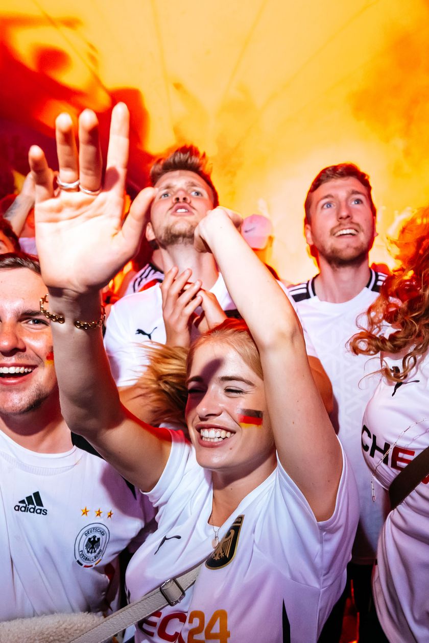 Feiernde und jubelnde Fans mit Trikots. 