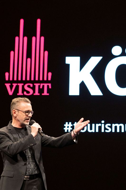 Herr Dr. Amann hält vor einer Bildschirmpräsentation einen Vortrag.