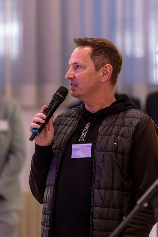 Uwe Weiler spricht fokussiert in ein Mikrofon.