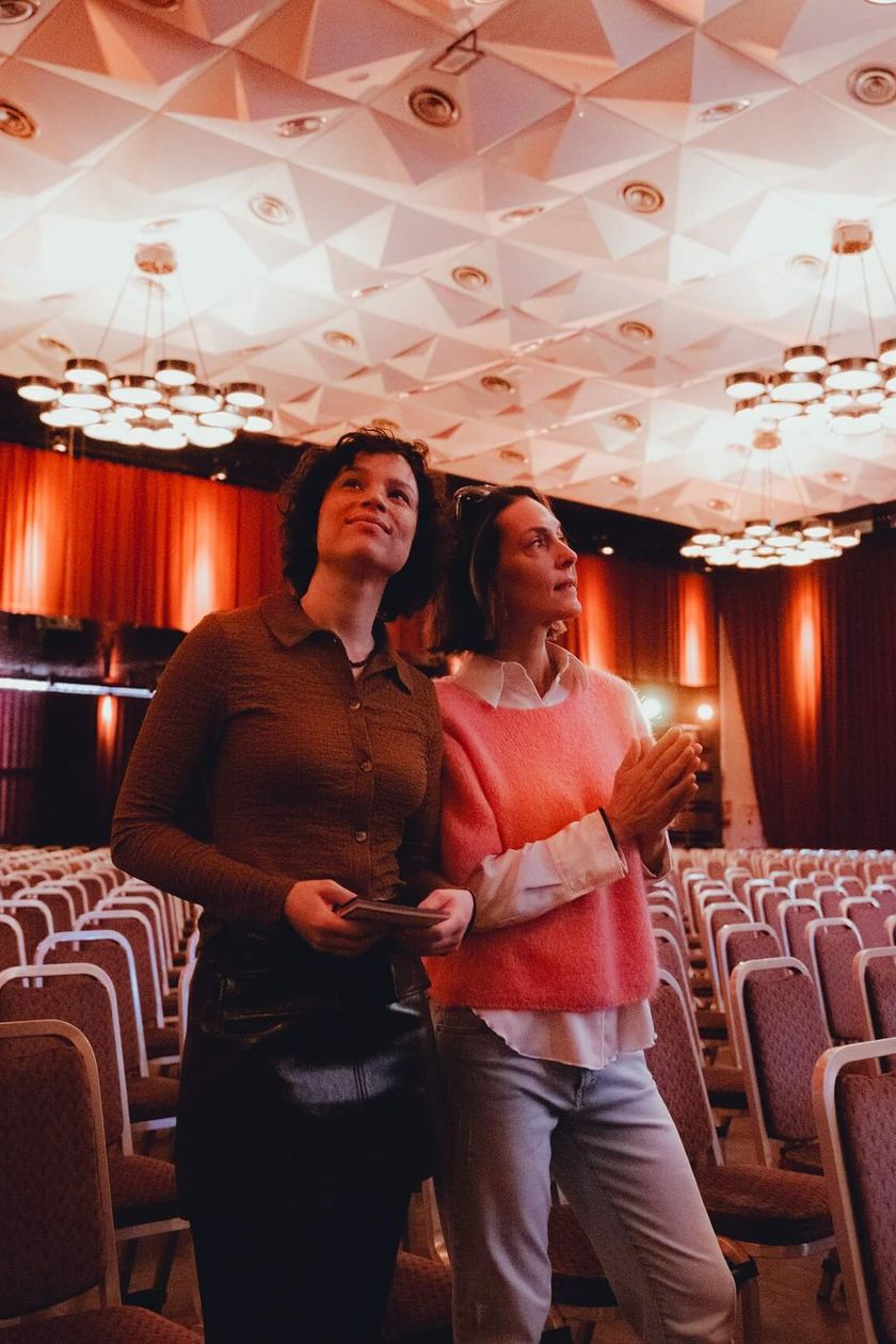 Zwei Personen stehen in einem gemütlich beleuchteten Saal und schauen sich um.