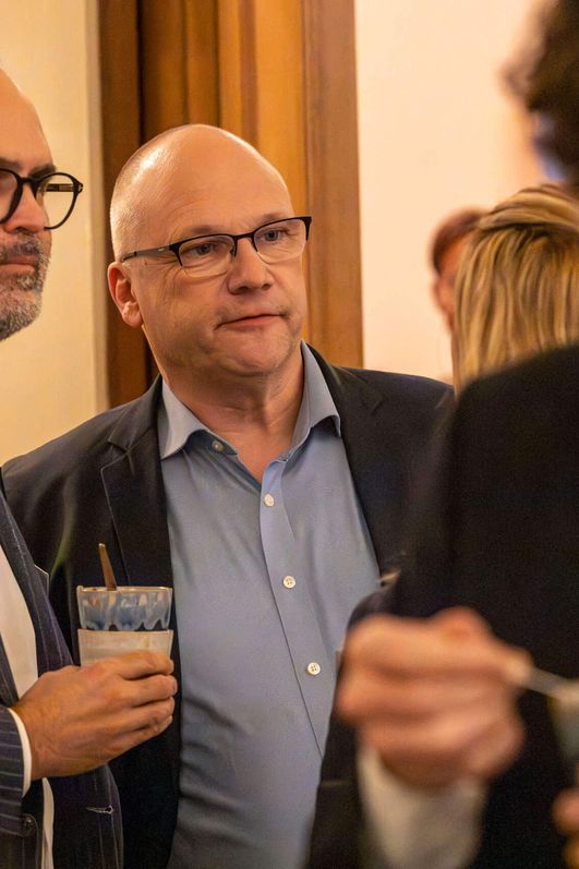 Zwei Männer mittleren Alters stehen nebeneinander und schauen interessiert in eine Richtung.