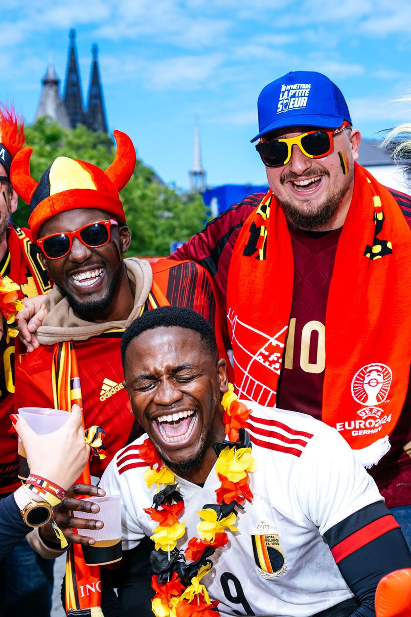 Sechs Personen posieren in roten Trikots und lustigen Kopfbedeckungen. Die Stimmung ist ausgelassen und fröhlich.