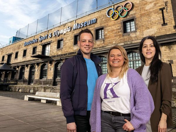 Drei Personen stehen vor dem Sport und Olympia Museum in Köln.