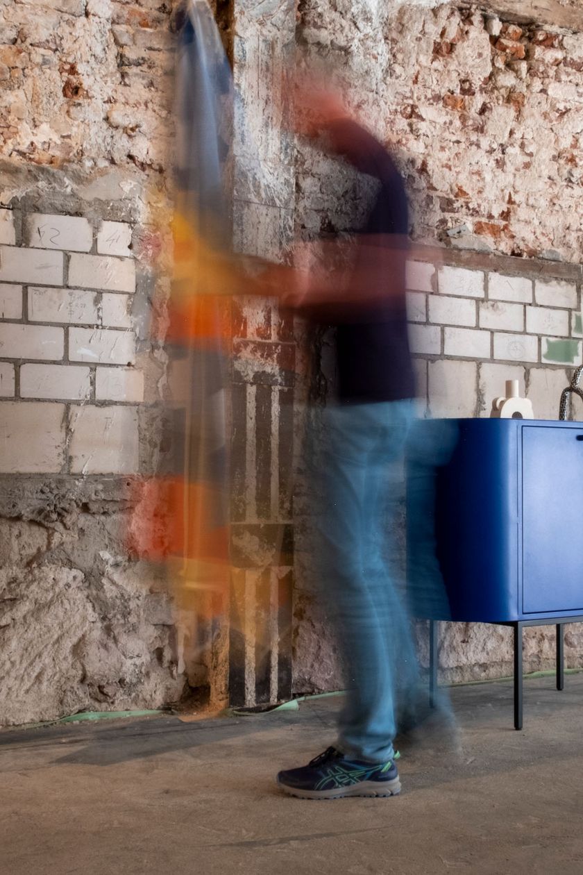 Vor einer unbehandelten Backsteinwand stehen blaue Desingmöbelstücke.