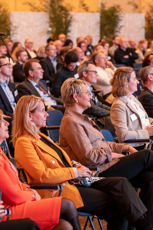 Auf dem Bild ist ein Publikum zu sehen, dass aufmerksam amüsiert zu hört.